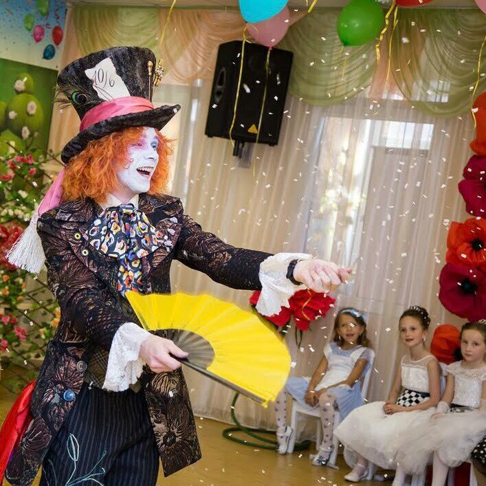 Шляпник из Алисы Чудес показывает детям фокусы